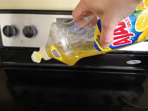 Squirting detergent on stovetop to clean it